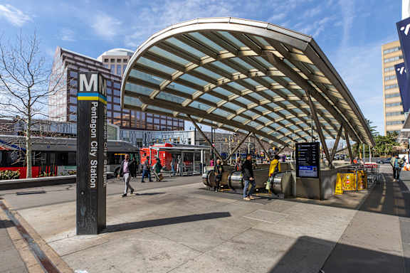 A train station with a large canopy and people walking around.
