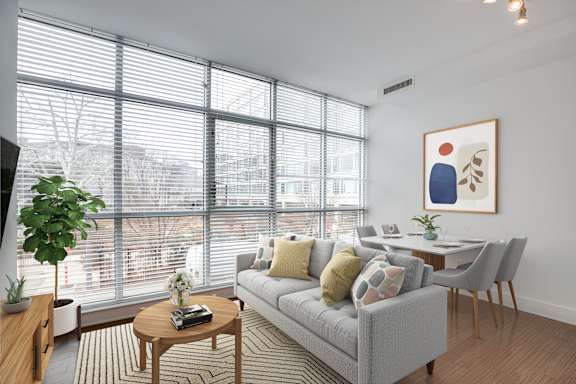 A living room with a grey couch, a coffee table, and a painting on the wall.