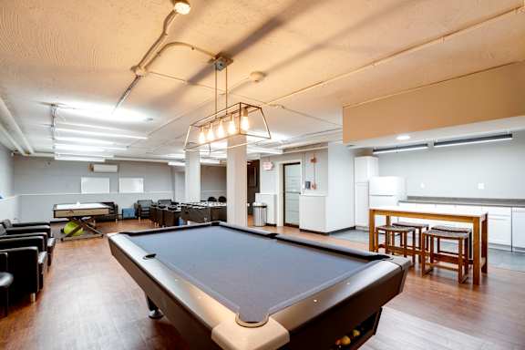 A pool table is in the middle of a room with a ping pong table and a ping pong net.