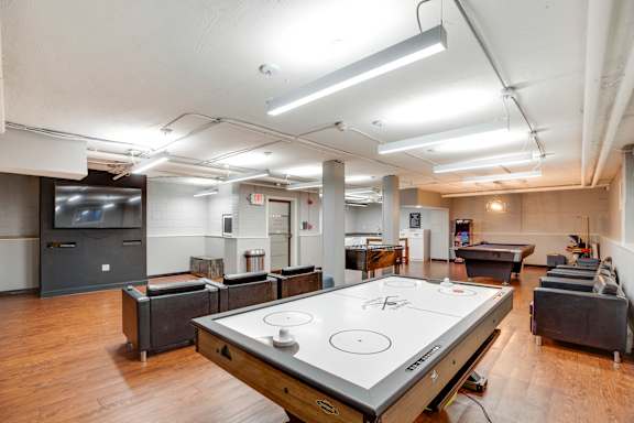 A room with a pool table in the center and a television on the wall.