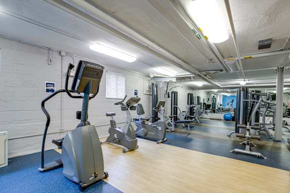 A gym with a variety of equipment including a treadmill, stationary bike, and weight machines.