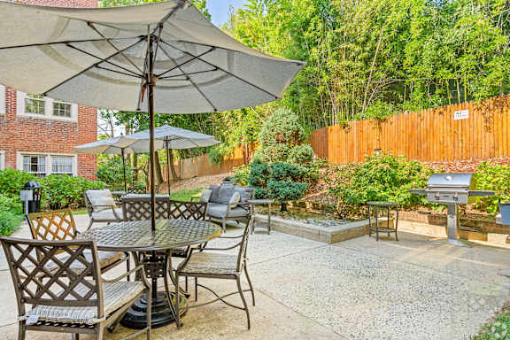 A patio with a table and chairs under an umbrella.