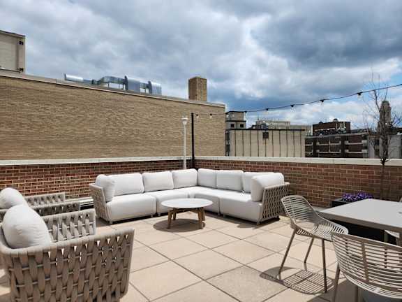 A patio with a white couch, wicker chair, and table.