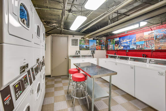 a laundry room with a table and red stools