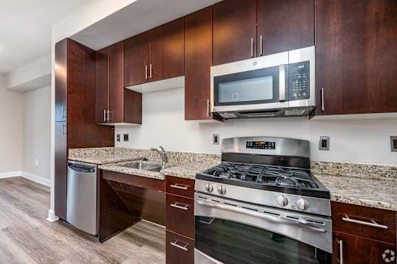 A modern kitchen with dark wood cabinets and stainless steel appliances. at Park Place at Petworth, Washington, Washington