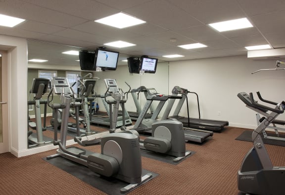 a gym with various exercise equipment and tv screens