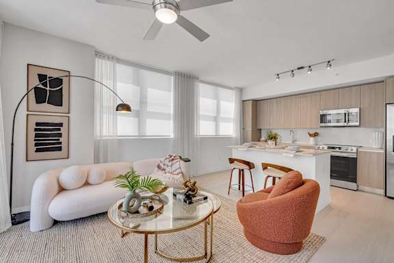 A modern living room with a white sofa, a coffee table, and a kitchen in the background.