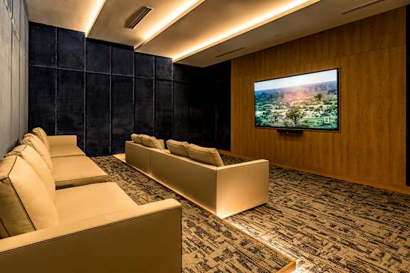 A modern living room with a large screen TV on the wall.