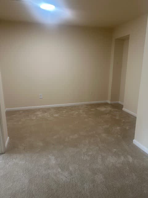 A room with a carpeted floor and a doorway leading to another room.