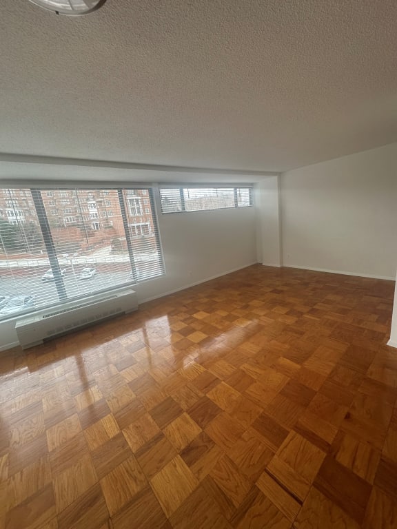 an empty living room with wood flooring and large windows