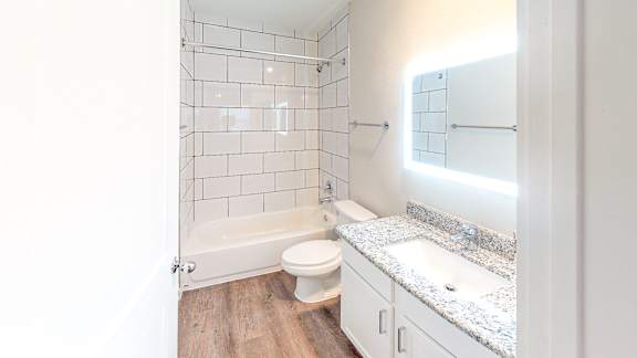 A white bathroom with a toilet, sink, and a tiled shower.