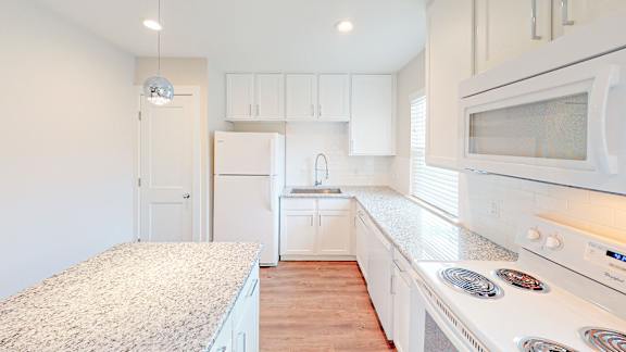 A kitchen with white cabinets and a granite countertop.
