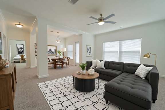A living room with a black couch, a coffee table, and a ceiling fan.