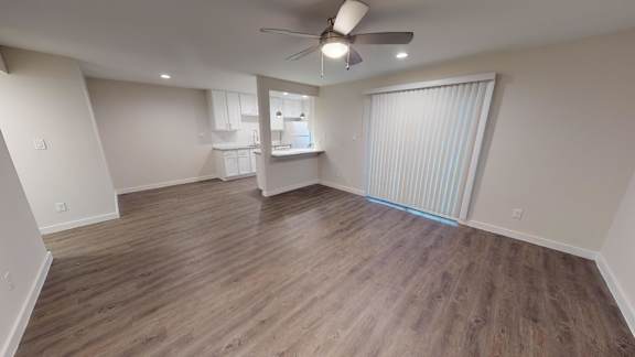 A room with a ceiling fan and wooden flooring.