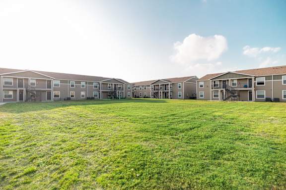 A row of apartment buildings with green grass in the foreground.