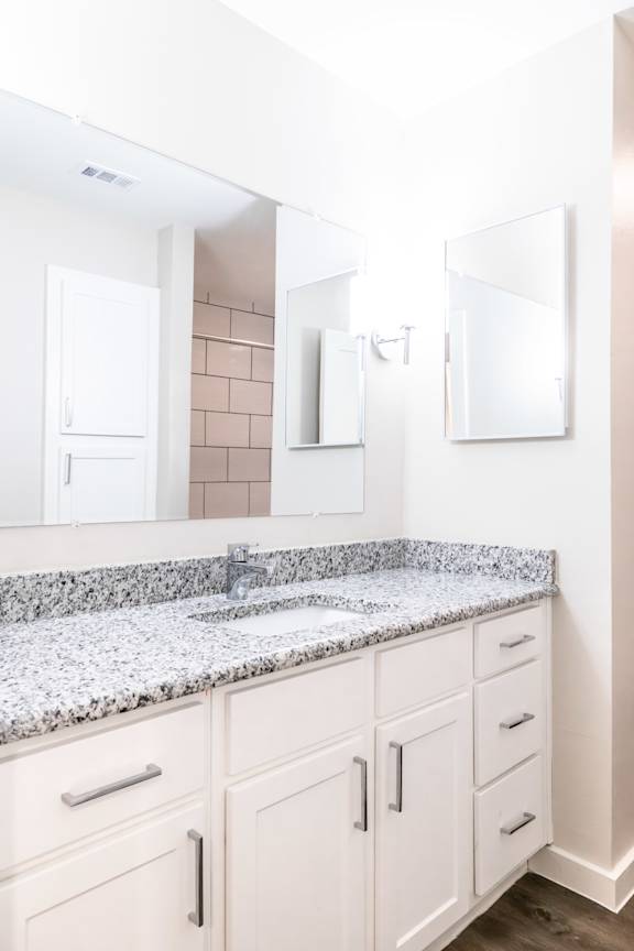 A bathroom with a granite countertop and white cabinets.