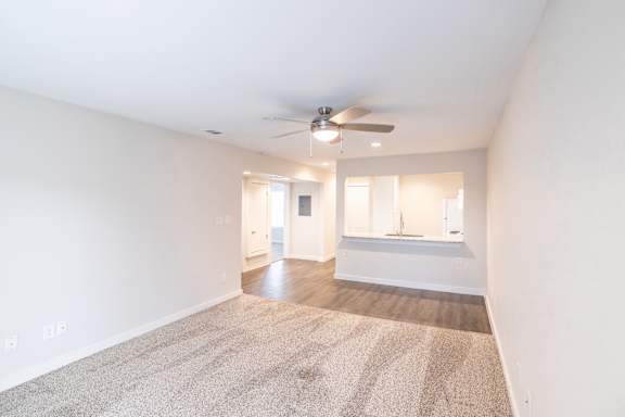 A spacious room with a ceiling fan and a carpeted floor.