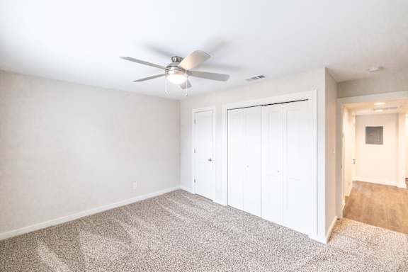 A room with a ceiling fan and carpeted floor.