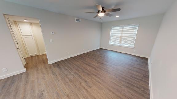 A room with a ceiling fan and wooden flooring.