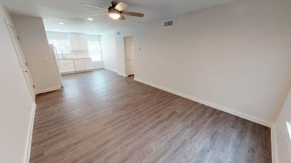 A room with a ceiling fan and wooden flooring.