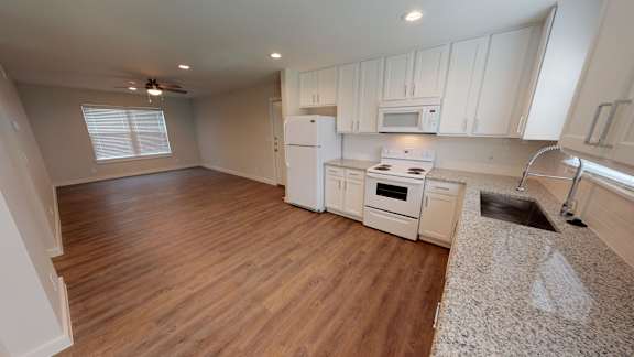 A kitchen with white appliances and wooden floors.