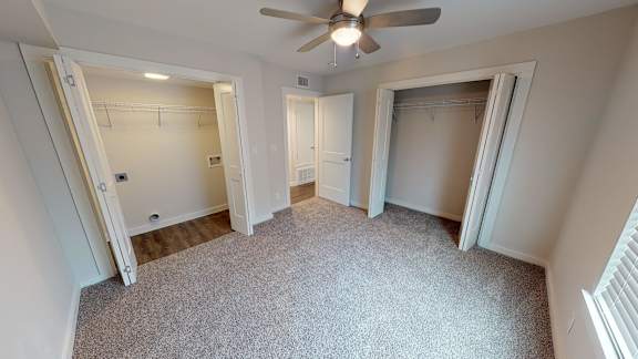 A room with a ceiling fan and carpeted floor.