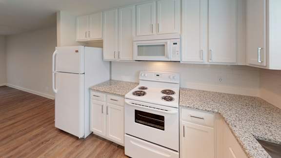 A white kitchen with a refrigerator, stove, and microwave.
