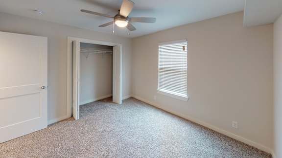 A room with a ceiling fan and a window with blinds.