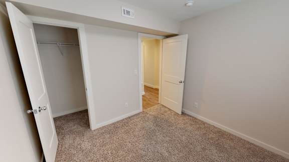 A room with a carpeted floor and two open doors.