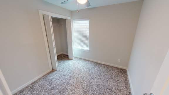 A room with a carpeted floor and a door leading to another room.