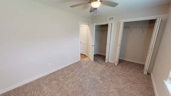 A room with a ceiling fan and carpeted floor.