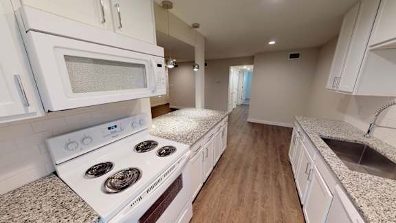 A white stove and microwave in a kitchen with wooden floors.