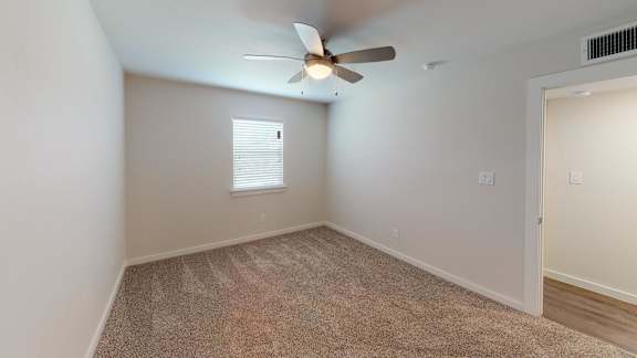 A room with a ceiling fan and carpeted floor.