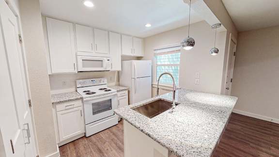 Kitchen with a granite counter top and white cabinets.