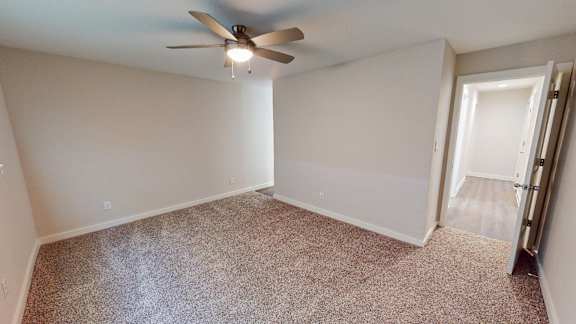 A room with a ceiling fan and carpeted floor.