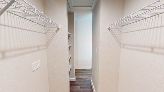 A hallway with white walls and a wooden floor.