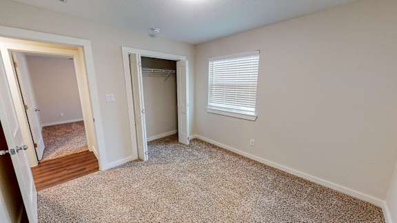 A room with a carpeted floor and a door leading to another room.