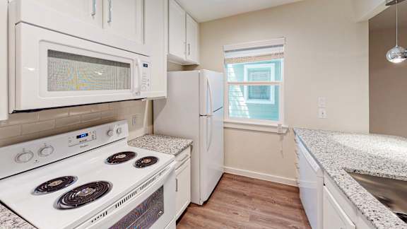 A white kitchen with a stove, microwave, and refrigerator.