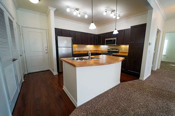 A kitchen with dark brown cabinets and a white island.