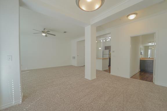 A spacious room with a ceiling fan and carpeted floor.