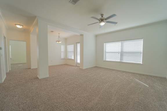 A spacious room with a ceiling fan and carpeted floor.
