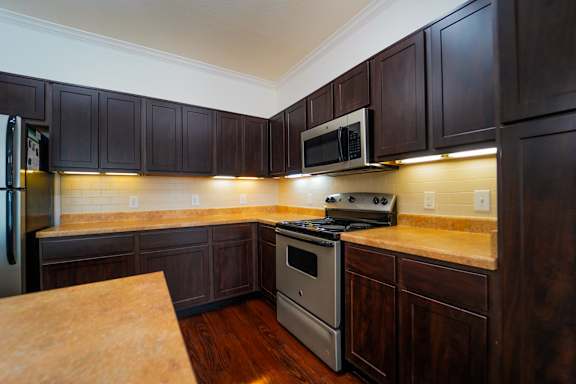 A kitchen with dark wood cabinets and stainless steel appliances.
