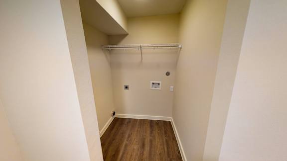 A small, empty room with a wooden floor and a white wall.