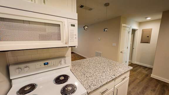 A kitchen with a white stove and microwave.