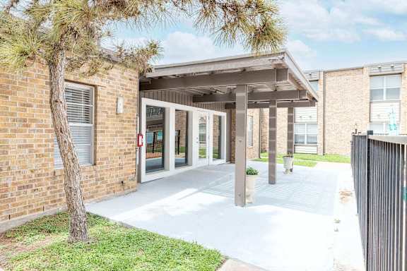 A building with a covered walkway and a tree in front.