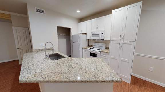 A kitchen with granite countertops and white cabinets.