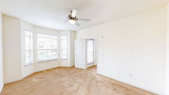 A room with a ceiling fan and carpeted floor.