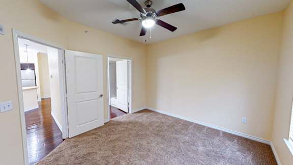 A room with a ceiling fan and carpeted floor.