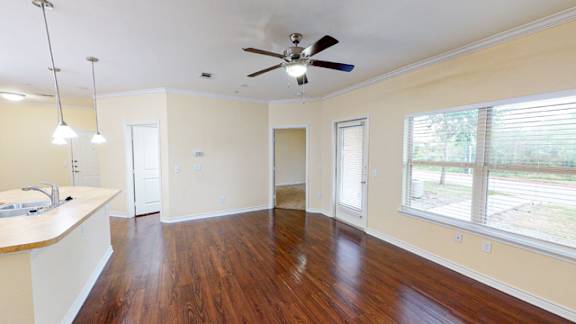 A room with a ceiling fan and wooden floors.