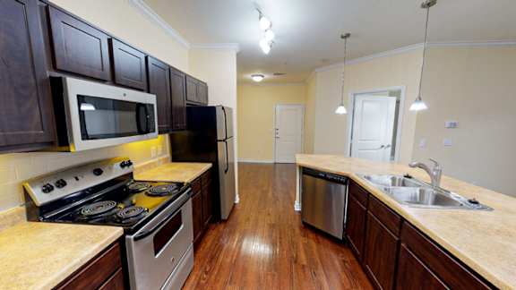 A kitchen with dark wood cabinets and a stainless steel dishwasher.